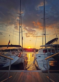 Sunset scene at the harbor as seen through the yachts moored at the pier in the old town of Nessebar