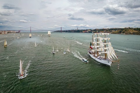 Aerial drone view of tall ships with sails sailing in Tagus river towards the Atlantic ocean in Lisbon