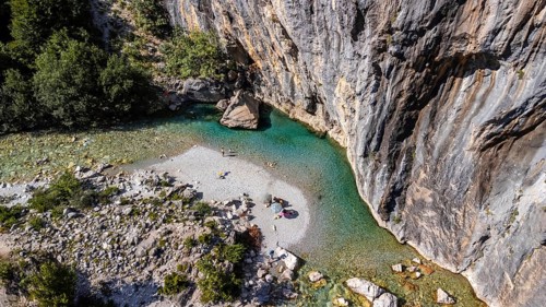Aerial drone view of small beach on turquoise river of Valbona valley