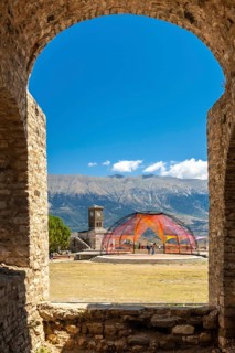 Arches of the fortress of the Ottoman castle of Gjirokaster or Gjirokastra and in the background the church with the clock tower. Albania