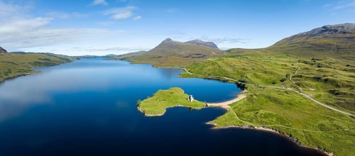 Aerial panorama of the freshwater loch Loch Assynt with the ruins of Ardvreck Castle on a peninsula