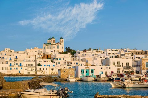 Traditional Greek whitewashed houses and church of Dormition of Mother of God as local landmark on hilltop by seafront on sunny day