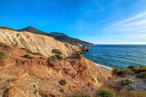 Beautiful sunset view of secluded and remote beach on sunny evening. High yellow cliffs