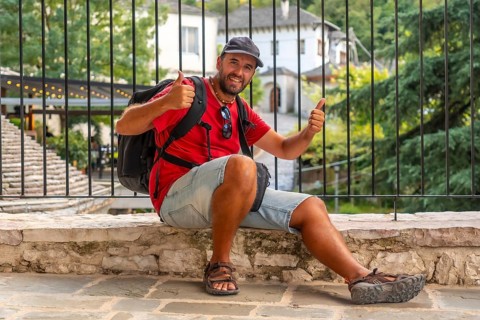 Portrait of a smiling tourist sitting resting on a viewpoint the city of Gjirokaster or Gjirokastra. Albanian