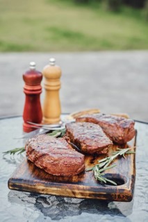Grilled New York strip steaks on the glass table on backyard