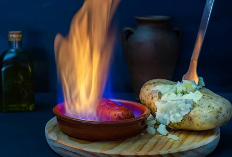 Boiled potato opened with a fork and chorizo in flames