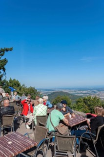 Tourists at the viewpoint in front of the Chateau du Haut Koenigsbourg. In the background the Upper Rhine Plain and the hilly landscape of the Black Forest