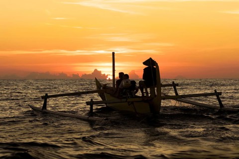 Small boat with outrigger in the sunrise