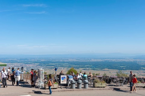 Tourists at the viewpoint in front of the Chateau du Haut Koenigsbourg. In the background the Upper Rhine Plain and the hilly landscape of the Black Forest