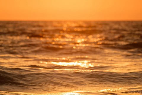 Ocean on sunset backlit with sun defocused blurred background