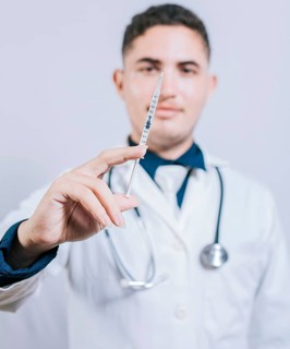 Caucasian doctor holding a syringe on isolated background. Closeup of doctor holding and showing a syringe isolated