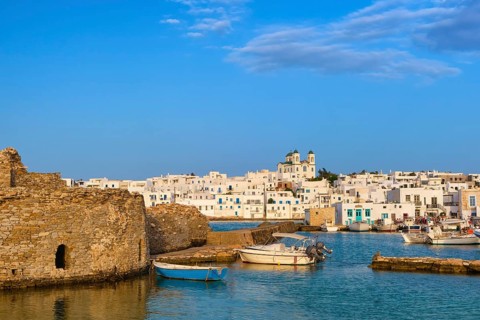 Traditional Greek whitewashed houses and church of Dormition of Mother of God as local landmark on hilltop by seafront on sunny day
