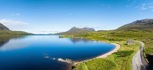 Aerial panorama of the freshwater loch Loch Assynt with the ruins of Ardvreck Castle