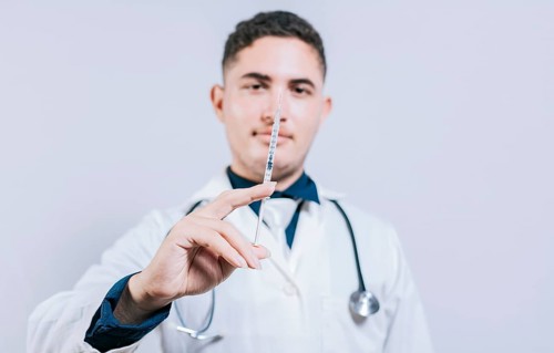 Closeup of doctor holding and showing a syringe isolated. Caucasian doctor holding a syringe on isolated background
