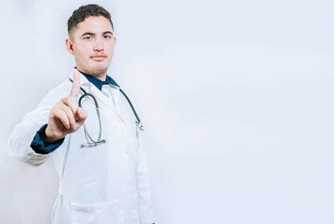 Doctor counting number ONE isolated. Handsome doctor counting number 1 on isolated background. Young doctor raising index finger isolated