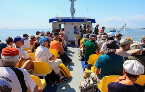 Sun deck of a tourist ship with tourists and crew member giving explanations via microphone