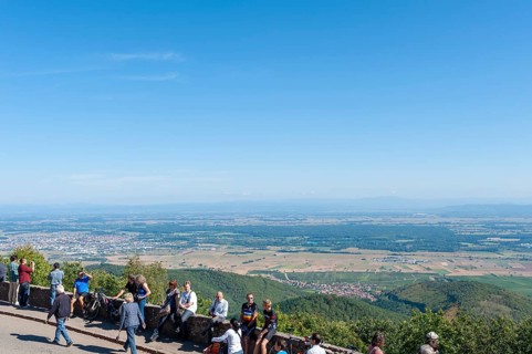 Tourists at the viewpoint in front of the Chateau du Haut Koenigsbourg. In the background the Upper Rhine Plain and the hilly landscape of the Black Forest