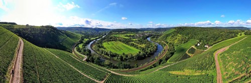Wiltinger Saarbogen. The river winds through the valley and is surrounded by vineyards and green forests. Kanzem