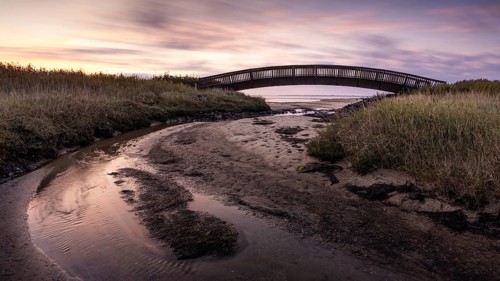 Colourful sunrise behind the Luegenbruecke on the mudflats in the east of the North Frisian island of Sylt