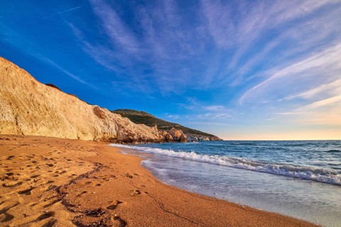 Beautiful low sun view of secluded and remote beach on sunny evening. High yellow cliffs