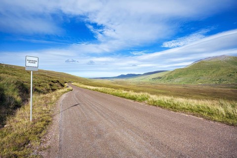 The single track road and tourist route or scenic road North Coast 500 also called NC500 with a passing place for oncoming traffic