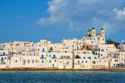 Traditional Greek whitewashed houses just by seafront on sunny day