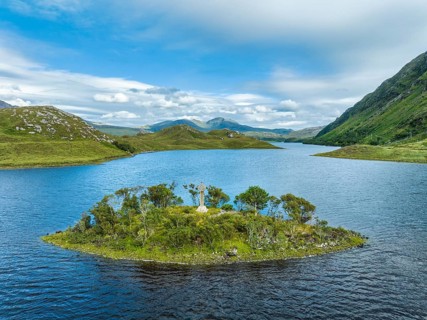 Aerial view of a small island with a Celtic stone cross in the freshwater loch of Loch Stack in the Northern Highlands
