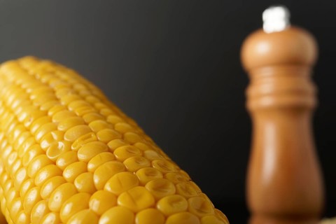 Corn cobs with pepper pot and spoon with butter