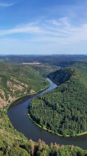 Aerial view of the Saar Loop. The Saar winds through the valley and is surrounded by green forests. Orscholz