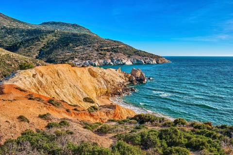 Beautiful sunset view of secluded and remote beach on sunny evening. High yellow cliffs