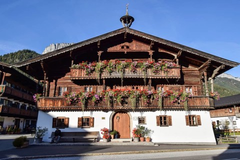 Large typical traditional Tyrolean farmhouse with balcony flowers in Waidring