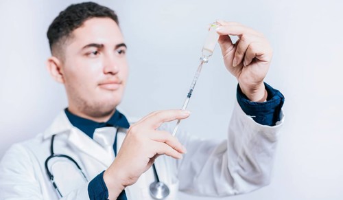 Handsome doctor holding syringe with antidote on isolated background. Closeup of doctor holding syringe and antidote isolated