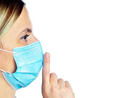 Woman wearing a face mask with her finger on her lips