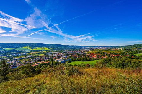 View over the city of Jena from the Galgenberg with the Kernberge in the background under blue sky and veil clouds