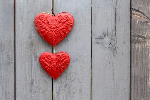 Two red metal hearts on a grey wooden gate