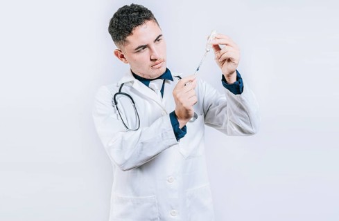 Doctor drawing antidote from a vial. Concept of doctor with disease antidote. Handsome doctor drawing medicine from a vial with copy space