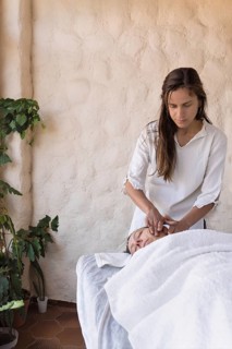 Young woman therapist and female patient having facial massage session massaging at beauty center