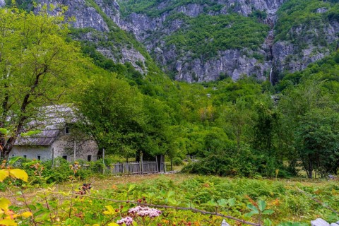 A wooden cabin under the Grunas waterfall in Theth National Park