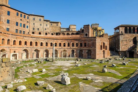 View of historic Forum of Traian Foro Traiano from antiquity with building in semicircle at rear with colonnade in foreground forecourt open space with column fragments remains of marble columns
