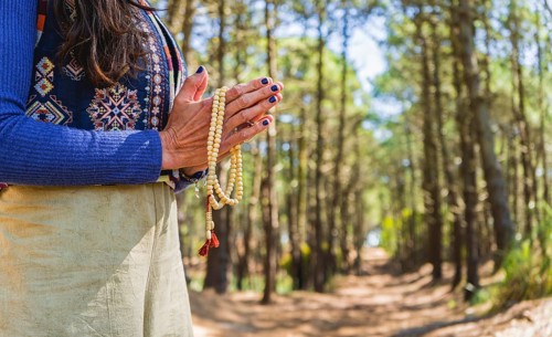 Close up of clasping hands holding a japa mala. Copy space
