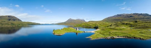 Aerial panorama of the freshwater loch Loch Assynt with the ruins of Ardvreck Castle on a peninsula
