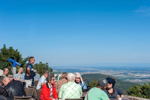 Tourists at the viewpoint in front of the Chateau du Haut Koenigsbourg. In the background the Upper Rhine Plain and the hilly landscape of the Black Forest