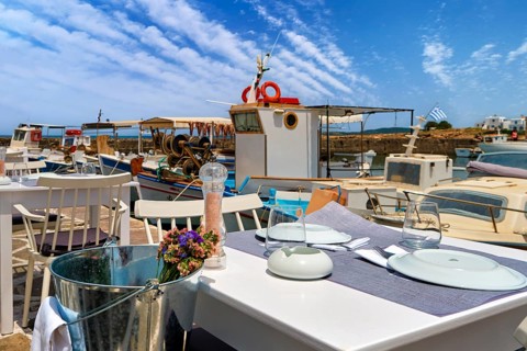 Tables and chairs of seafood restaurant by waterfront of Naoussa bay