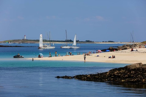 Sandy beach beach with bathers and sailboats