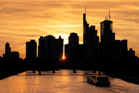 A ship sails at sunset on the Main towards the silhouette of Frankfurt's banking skyline