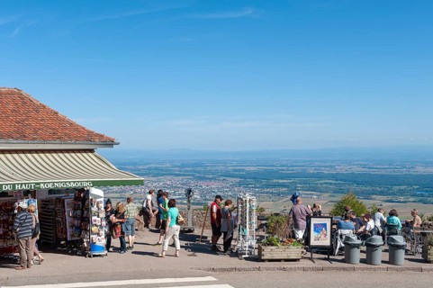 Tourists at the viewpoint in front of the Chateau du Haut Koenigsbourg. In the background the Upper Rhine Plain and the hilly landscape of the Black Forest