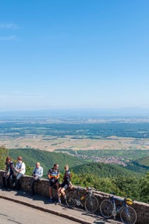 Tourists at the viewpoint in front of the Chateau du Haut Koenigsbourg. In the background the Upper Rhine Plain and the hilly landscape of the Black Forest