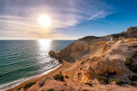 Beautiful low sun view of secluded and remote beach on sunny evening. High yellow cliffs
