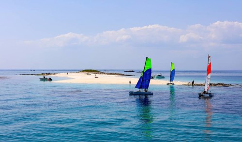 Sailing catamarans of the sailing school Les Glenans in front of the sandy beach of Ile de Guiriden
