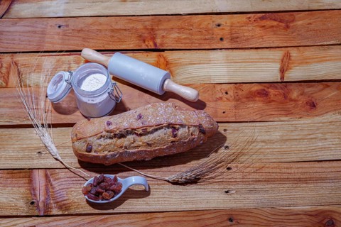 Loaf of rustic raisin bread on a wooden table with flour